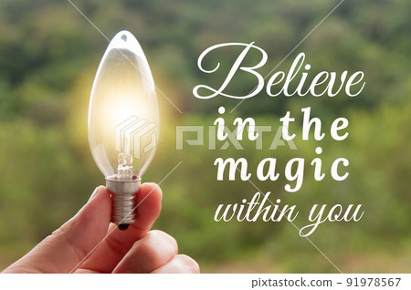 Motivational and Inspirational quote - Believe in the magic within you. Hand holding light bulb with blurred background. Motivational and Inspirational quote - Believe in the magic within you. Hand holding light bulb with blurred background. 91978567