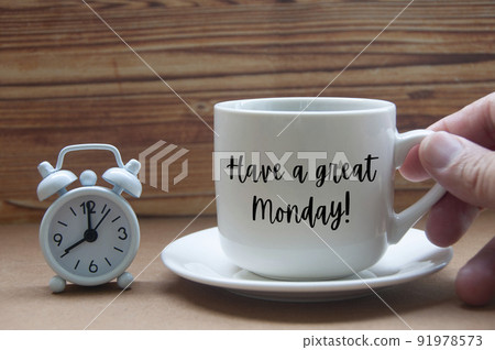 Morning greeting concept - Have a great Monday text on coffee cup with alarm clock on wooden table. 91978573