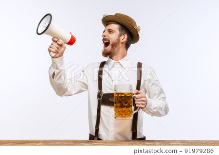 Astonished man wearing traditional fest Bavarian or German outfit with big beer glass shouting at megaphone about Oktoberfest start. Party, holiday, ad,sales concept Astonished man wearing traditional fest Bavarian or German outfit with big beer glass shouting at megaphone about Oktoberfest start. Party, holiday, ad,sales concept 91979286