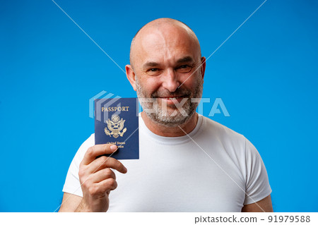 Middle age man holding passport with a happy face against blue background Middle age man holding passport with a happy face against blue background 91979588