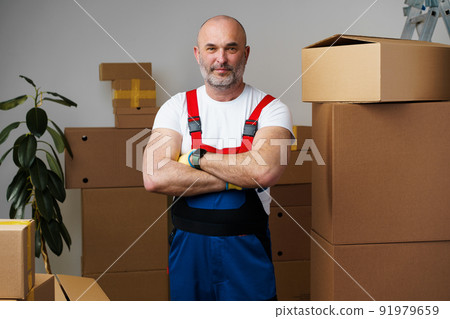 Portrait of a middle-aged man mover in uniform standing against stacked boxes 91979659