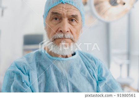 Professional senior surgeon in uniform standing in operating room, ready to work on patient 91980561