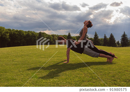 Young healthy couple doing acro yoga in the sunny summer park. Fitness and healthy lifestyle 91980575