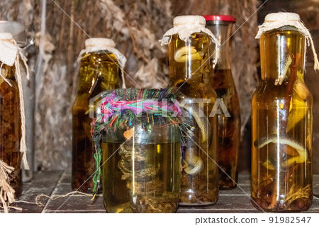 Alcoholic drink, tincture using a snake. Alcoholic drink infused with snake venom. Homemade alcohol with the addition of snake and herbs. A potion with medicinal harbs and a snake. 91982547