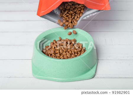 Pouring pet food into a bowl on the floor. 91982901