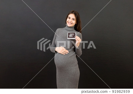 Cute Pregnant Lady Posing With Baby Sonography Photo Near Colored background. Concept of pregnancy, gynecology, medical test, maternal health 91982939
