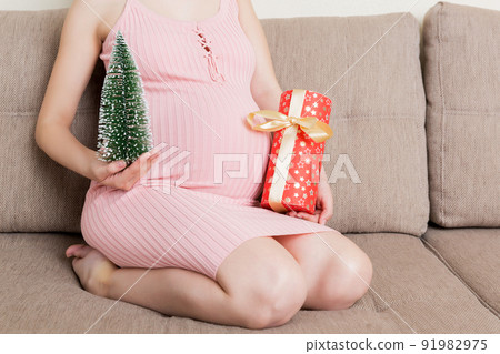 Happy pregnant woman holding Christmas gift box in her hands. New year concept 91982975