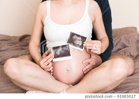 Portrait of young happy married couple hold ultrasound picture. Diverse man and pregnant woman show sonogram image on kid child, excited for parenthood. Parenting concept Portrait of young happy married couple hold ultrasound picture. Diverse man and pregnant woman show sonogram image on kid child, excited for parenthood. Parenting concept 91983017