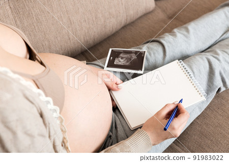Top view caring future mother writing diary with ultrasound. pregnant woman tummy making notes feeling during pregnancy or creating scrapbook Top view caring future mother writing diary with ultrasound. pregnant woman tummy making notes feeling during pregnancy or creating scrapbook 91983022