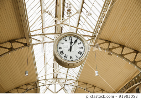 Round Roman clock at railway or subway station. Twelve o'clock, five past twelve pm, close-up Round Roman clock at railway or subway station. Twelve o'clock, five past twelve pm, close-up 91983058