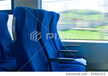 interior of commuter passenger train car, row of chairs and a motion-blurred landscape outside the window interior of commuter passenger train car, row of chairs and a motion-blurred landscape outside the window 91983123