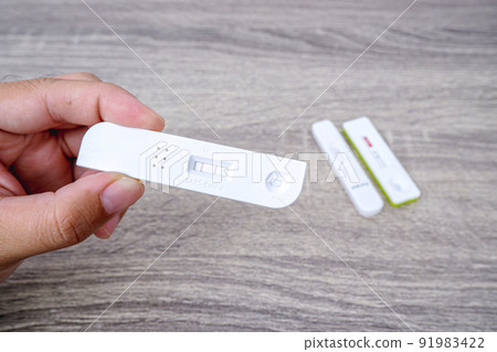 Covid-19 Test cassette with positive result in the hand on wooden background 91983422