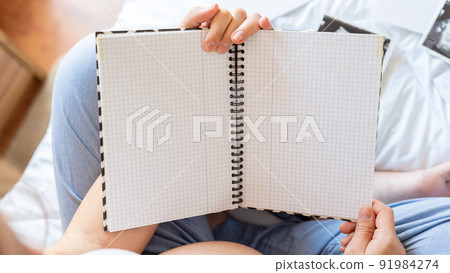 Pregnant writing baby list. Beautiful pregnancy woman writing check list. Happy pregnant lady holding notepad. Pregnancy, maternity, healthcare concept. 91984274