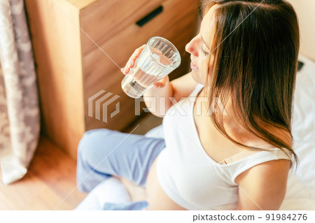 Pregnant drinking woman. Beautiful pregnancy drink water. Happy pregnant lady holding glass of water. Concept of maternity, expectation. 91984276