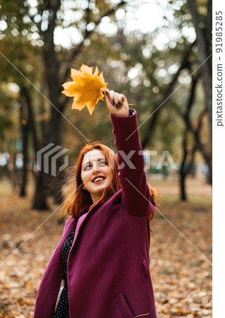 Autumn fashion, earth tones style, bright fall color palette. Portrait of red-haired girl in purple coat Autumn fashion, earth tones style, bright fall color palette. Portrait of red-haired girl in purple coat 91985285