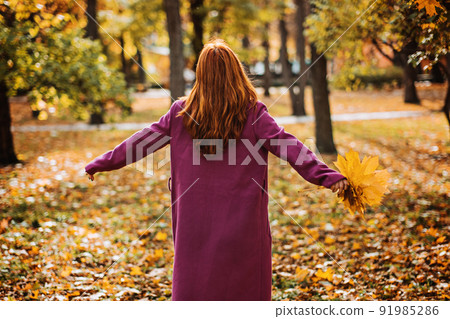 Back view faceless portrait of red-haired girl with fall leaves in hand. Autumn Portrait of happy woman Back view faceless portrait of red-haired girl with fall leaves in hand. Autumn Portrait of happy woman 91985286