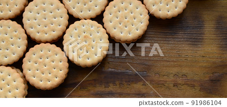 A round sandwich cookie with coconut filling lies in large quantities on a brown wooden surface. Photo of edible treats on a wooden background with copy space A round sandwich cookie with coconut filling lies in large quantities on a brown wooden surface. Photo of edible treats on a wooden background with copy space 91986104