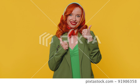 Redheaded woman raises thumbs up agrees or gives positive reply recommends advertisement likes good 91986358