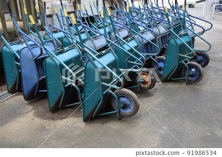 Multiple wheelbarrows leaning against 91986534