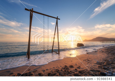 Wooden swing in beautiful blue sea with waves, sandy beach 91986541