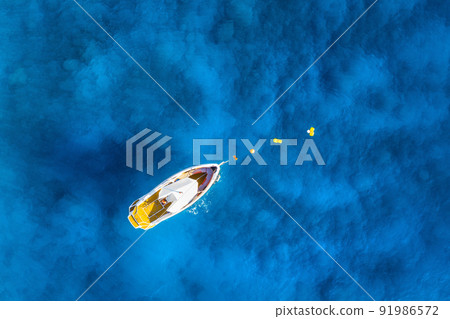 Aerial view of alone boat in blue sea at sunset in summer Aerial view of alone boat in blue sea at sunset in summer 91986572