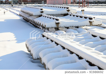 A lot of old rails and sleepers are stacked in a railway warehouse in winter. The concept of renewing a worn-out railway track 91986692
