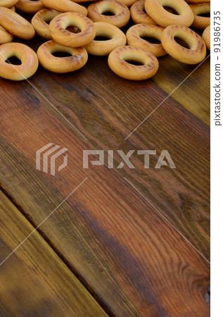 A lot of fresh yellow bagels lie on the surface of the old dark wood. A popular kind of flour products. One of the traditional Russian treats for tea A lot of fresh yellow bagels lie on the surface of the old dark wood. A popular kind of flour products. One of the traditional Russian treats for tea 91986735