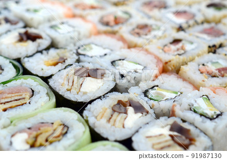 Close-up of a lot of sushi rolls with different fillings. Macro shot of cooked classic Japanese food. Background image Close-up of a lot of sushi rolls with different fillings. Macro shot of cooked classic Japanese food. Background image 91987130