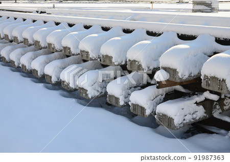 A lot of old rails and sleepers are stacked in a railway warehouse in winter. The concept of renewing a worn-out railway track A lot of old rails and sleepers are stacked in a railway warehouse in winter. The concept of renewing a worn-out railway track 91987363