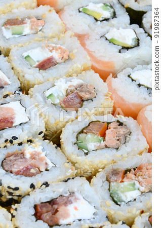 Close-up of a lot of sushi rolls with different fillings. Macro shot of cooked classic Japanese food. Background image Close-up of a lot of sushi rolls with different fillings. Macro shot of cooked classic Japanese food. Background image 91987364
