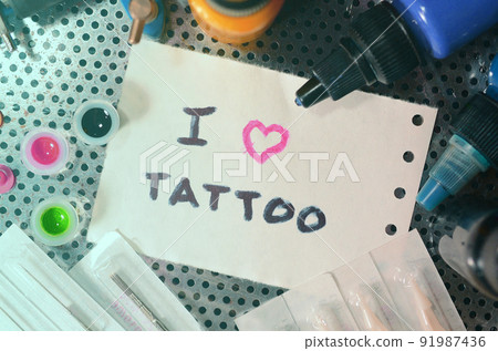 I love tattoo. The text is written on a small sheet of paper among various equipment for tattooing 91987436