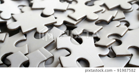 Close-up of a pile of uncompleted elements of a white puzzle. A huge number of rectangular pieces from one large white mosaic Close-up of a pile of uncompleted elements of a white puzzle. A huge number of rectangular pieces from one large white mosaic 91987582