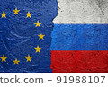 European Union vs Russia - Cracked concrete wall painted with a EU flag on the left and a Russian flag on the right stock photo 91988107