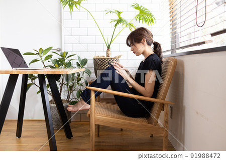 Cute woman looking at a smartphone in the room Cute woman looking at a smartphone in the room 91988472