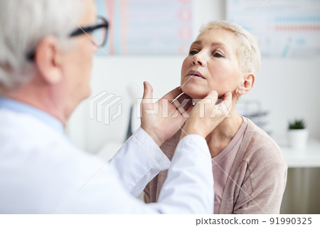 Over shoulder view of qualified cancer doctor touching neck of mature patient while checking size of lymph nodes Over shoulder view of qualified cancer doctor touching neck of mature patient while checking size of lymph nodes 91990325