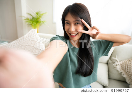 Pretty young asian female with big smile sitting at living room 91990767