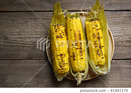 sweet corn food , sweet corn cooked on wooden plate background, ripe corn cobs grilled sweetcorn for food vegan dinner or snack - top view 91991379