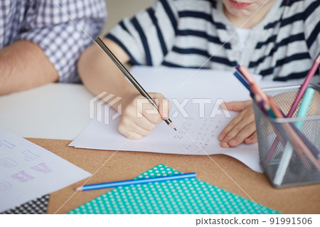 Close-up of unrecognizable elementary student boy sitting at table and solving mathematical tasks on paper 91991506