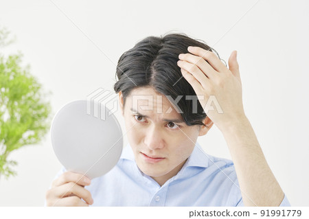 A man checking his hair with a hand mirror 91991779