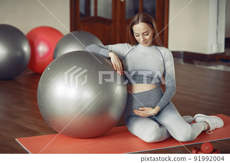Pregnant girl in a gym. Sports girl in a sportswear. Pregnant girl in a gym. Sports girl in a sportswear. 91992004