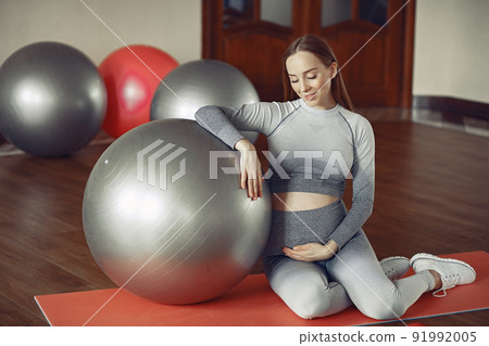 Pregnant girl in a gym. Sports girl in a sportswear. Pregnant girl in a gym. Sports girl in a sportswear. 91992005