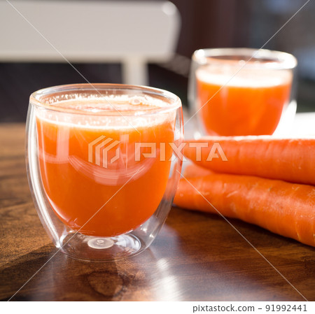 Organic carrot juice in glass on dark wooden background Organic carrot juice in glass on dark wooden background 91992441