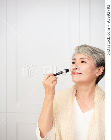 Portrait of mature asian woman 50s with holding make up brush. 91992792