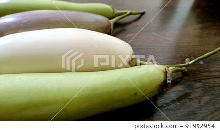 Closeup of organic white and green fresh eggplant or brinjal isolated on wooden background Closeup of organic white and green fresh eggplant or brinjal isolated on wooden background 91992954