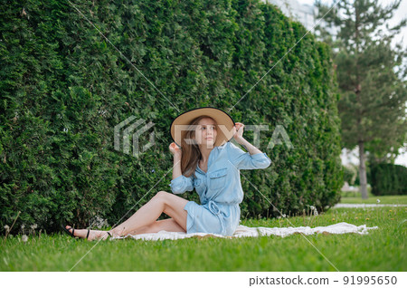 Romantic girl with hat on picnic in park Romantic girl with hat on picnic in park 91995650