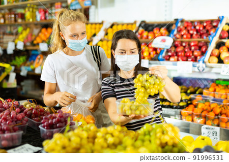 Young girl and her mother in face masks, choosing grape at grocery Young girl and her mother in face masks, choosing grape at grocery 91996531