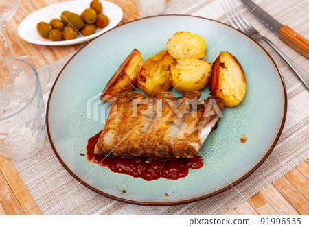 Baked under sauce pork ribs at plate with potatoes Baked under sauce pork ribs at plate with potatoes 91996535