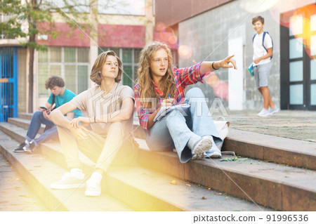Teenagers sitting on stairs beside school Teenagers sitting on stairs beside school 91996536