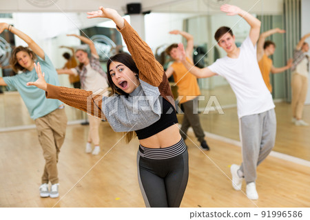 Cheerful emotional teen girl training dance movements in choreography class Cheerful emotional teen girl training dance movements in choreography class 91996586