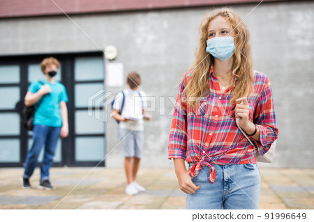 Portrait of teenage girl in face mask for disease protection walking after lessons at sunny day during pandemic 91996649